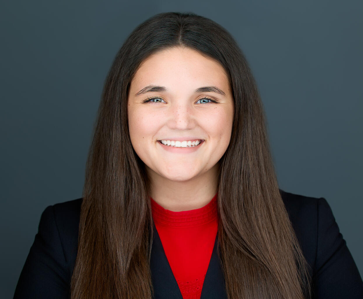 Kris Fores Owner of Kris Flores Insurance Solutions LLC Headshot of Regan Bailey administrator at Kris Flores Insurance Solutions LLC, wearing a dark jacket and red top, over the shoulder length hair of brown color.