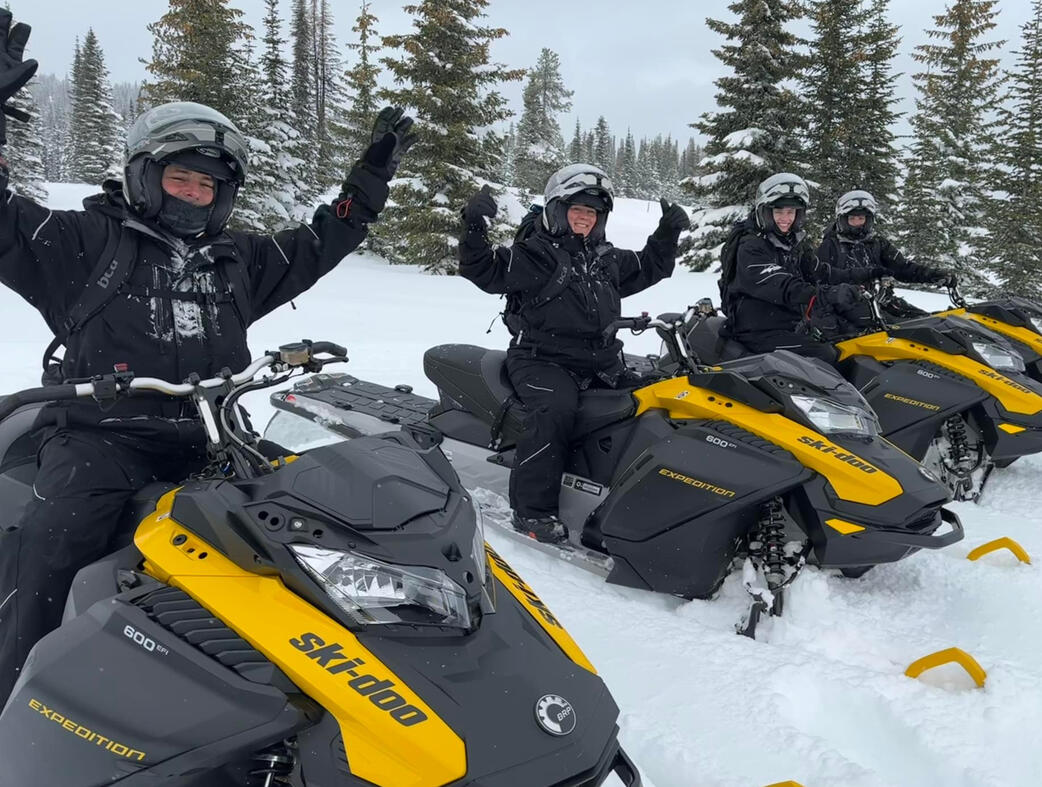 Kris Fores vacation Kris and Family sat on snow bikes in a hill with snow and trees